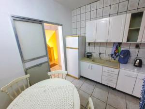 eine Küche mit einem Tisch und einem weißen Kühlschrank in der Unterkunft Apartamento na Sepé em Capão da canoa in Capão da Canoa
