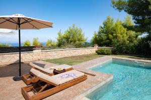 een zwembad met 2 ligstoelen en een parasol bij Spa Villa Sunny in Hanioti
