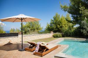 een parasol en stoelen naast een zwembad bij Spa Villa Sunny in Hanioti