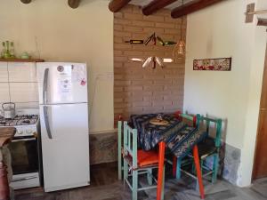 cocina con nevera blanca y mesa con sillas en La Arenosa 1, en Cafayate