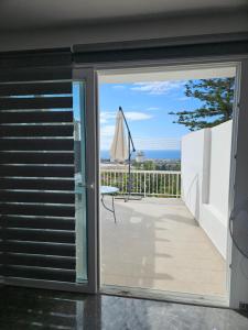 een glazen schuifdeur die toegang geeft tot een balkon met een parasol bij Anton Luxury Villa SeaView by Emmelia Group in Klorakas