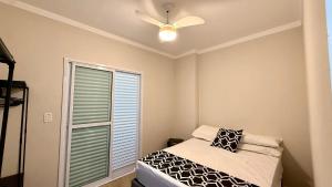 een slaapkamer met een bed en een plafondventilator bij Condomínio Edifício Viena in Vila Balneária