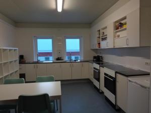 a kitchen with white cabinets and a table and two windows at Hotel Arctic Circle in Kangerlussuaq