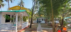een geel en wit huis met palmbomen ervoor bij Bal Ganesha beach resort in Canacona