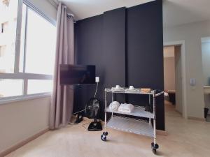 Zimmer mit einem TV und einem Wagen mit Schuhen in der Unterkunft Centro 15 in Belo Horizonte