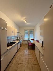 una grande cucina con mobili bianchi e un tavolo di RuhrPott Rooms & Flats a Gelsenkirchen
