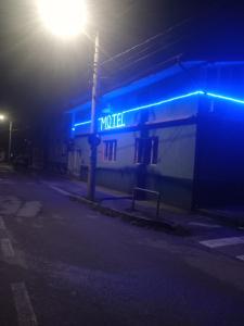 ein Gebäude mit einem blauen Neonschild an einer Straße in der Unterkunft Liliacului in Marghita