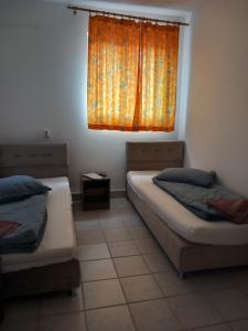 1 Schlafzimmer mit 2 Betten und einem Fenster mit orangefarbenem Vorhang in der Unterkunft Liliacului in Marghita
