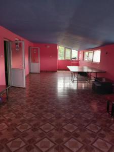 ein leerer Raum mit rosa Wänden, einem Tisch und einem Kühlschrank in der Unterkunft Liliacului in Marghita