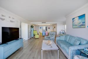 un soggiorno con un divano blu e una TV di Lighthouse Point 228- Stunning Beachside Residence a Sanibel
