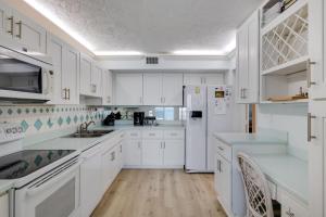 una cucina bianca con armadi bianchi ed elettrodomestici bianchi di Lighthouse Point 228- Stunning Beachside Residence a Sanibel