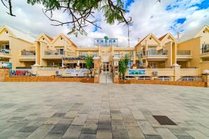 een groot geel gebouw met een plein ervoor bij Yucca Park duplex in Adeje