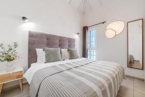 een witte slaapkamer met een groot bed en een spiegel bij Yucca Park duplex in Adeje +9 foto's