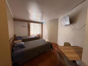 a room with two beds and a table and a window at Hostal La Reserva - Pisco in Pisco