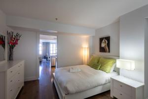 a bedroom with a white bed with green pillows at Les Immeubles Charlevoix - Le 1176 in Quebec City