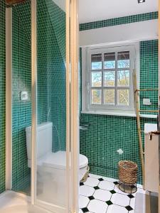 bagno piastrellato verde con servizi igienici e finestra. di Villa Elysia YourHostHelper a Touques