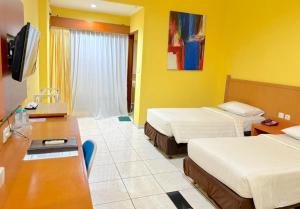 een hotelkamer met twee bedden en een bureau bij Pondok Jatim Park Hotel & Café in Batu