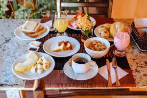 a table topped with plates of breakfast foods and drinks at VELINN Pousada Face Norte in Ilhabela
