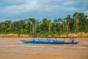 een blauwe boot in het water op een rivier bij Hacienda Tambopata Lodge in Tambopata