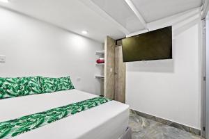 a small bedroom with a bed and a flat screen tv at Casa Hotel Ecosuite in Cali +8 photos