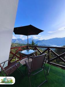 a table and chairs on a balcony with an umbrella at Chalet Maranatha Vista Única Represa de Chivor in Macanal