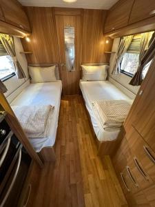 two beds in a small room with wooden floors at RV Palm Oasis in Liwa