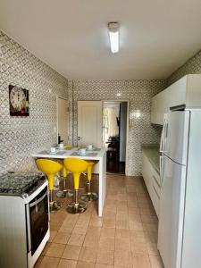 eine Küche mit gelben Barhockern und einem Kühlschrank in der Unterkunft Descanso garantido no centro de Foz in Foz do Iguaçu + 4 Fotos