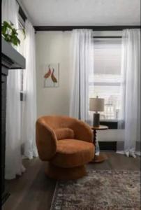 a brown chair in a living room with a window at 3BR Downtown-Old Salem Oasis in Winston-Salem