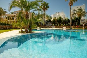a large swimming pool with palm trees and buildings at Sunny Place Oasis del Sol in Arenales del Sol