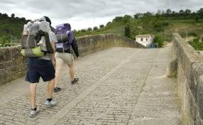 two people with backpacks walking over a bridge at Casa Batit in Viscarret-Guerendiáin