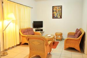 a living room with wicker chairs and a tv at Rachel's Apartments in Paramaribo