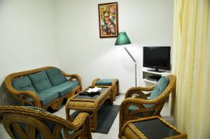 a living room with a couch and chairs and a tv at Rachel's Apartments in Paramaribo
