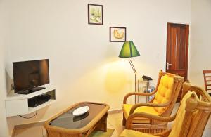 a living room with a tv and two chairs and a coffee table at Rachel's Apartments in Paramaribo