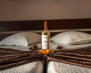 Una botella de vino encima de dos camas. en Pensiunea Taka, en Orşova 19 fotos más