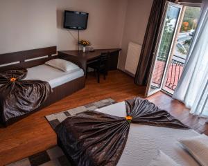 Un dormitorio con dos camas y un escritorio y un televisor. en Pensiunea Taka, en Orşova