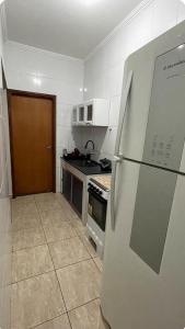 a white kitchen with a refrigerator and a stove at Casa Gêmeas 1 in Andradina