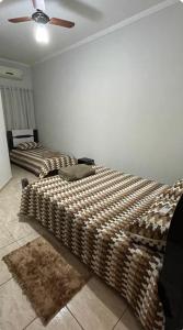 two beds in a room with a ceiling fan at Casa Gêmeas 1 in Andradina