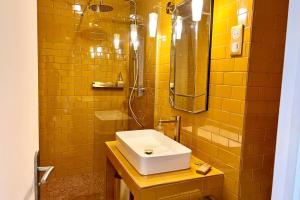 ein gelb gefliestes Badezimmer mit Waschbecken und Dusche in der Unterkunft Le Petit Jaune - Studio - Terrasse & Plage Pointe Rouge in Marseille