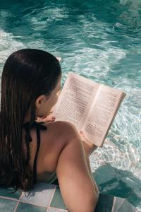 a woman sitting in a swimming pool reading a book at Pousada Maracaju in Porto De Galinhas +98 photos