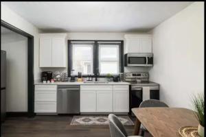a kitchen with white cabinets and a sink and a table at 3BR Downtown-Old Salem Oasis in Winston-Salem