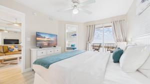 een witte slaapkamer met een bed en een televisie bij Surf Beach Treasure Island Resort in St Pete Beach
