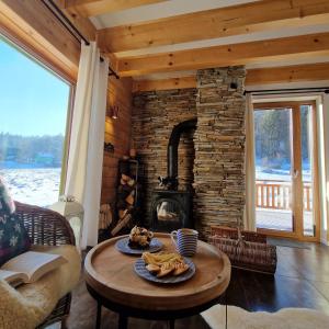 sala de estar con chimenea de piedra y mesa en Górskie Siedlisko - 3 Chaty, en Rycerka Górna