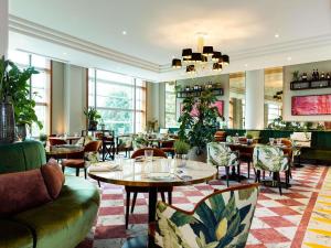 Un restaurante con mesas, sillas y ventanas. en Sofitel Luxembourg Europe, en Luxemburgo