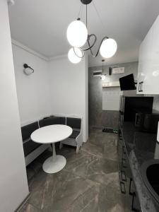 una stanza con un tavolo bianco, una panca e delle luci di Ideal House Rent a Petroşani