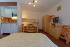 a bedroom with a bed and a table and a kitchen at Studio Serre Chevalier 300m des pistes in Saint-Chaffrey +4 photos