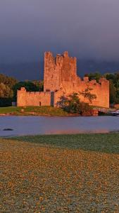 an old castle sitting on top of a body of water at Earls Court House in Killarney