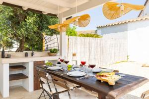een houten tafel met eten en wijnglazen op een patio bij Casa Rifa in Serramanna