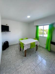a dining room with a table and green chairs at Departamentos Los Manantiales in Villa Gesell