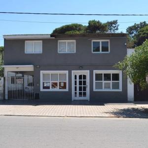 a gray house with white windows on a street at Departamentos Los Manantiales in Villa Gesell