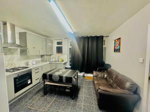 a living room with a couch and a table in a kitchen at Heathrow roomzzzz BnB in Hayes